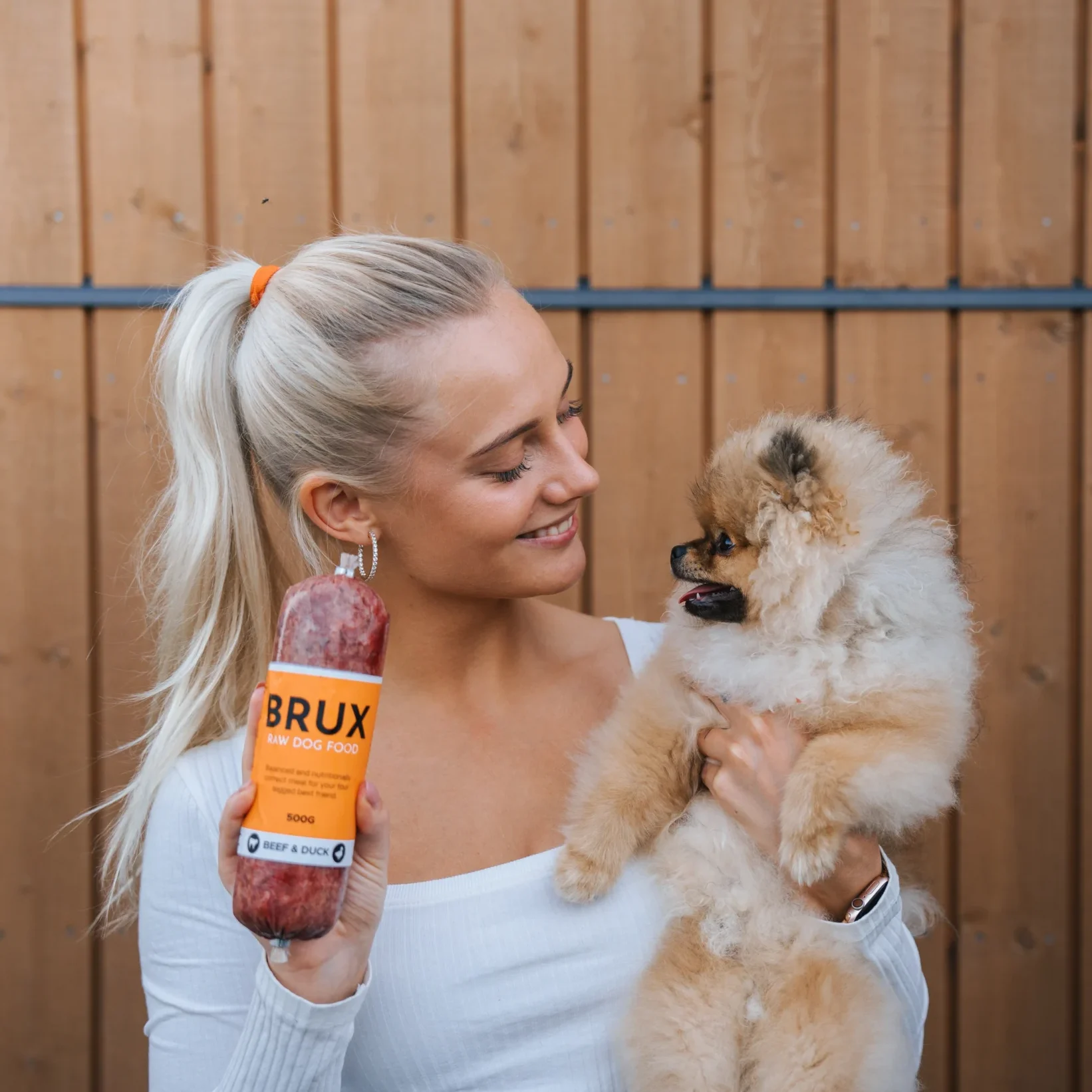 Dogmom with her pomeranian puppy holding BRUX raw dog food in her hand